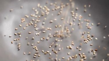 Doğal biyoorganik susam tohumları gri bir mutfak kasesine dökülüyor. Lezzetli malzeme. Ağır çekim. Kapat.