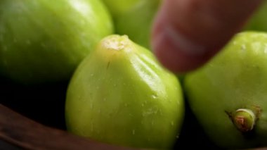 Erkek el, ahşap kaseden taze yeşil incir alıyor. Sağlıklı organik meyveler