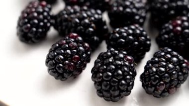 Beyaz seramik bir yüzeyde taze olgun, sulu yaban mersini. Tatlı, sağlıklı organik vitamin meyveleri. Döndürme. Makro çekim