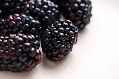 Beyaz seramik bir yüzeyde taze olgun, sulu yaban mersini. Tatlı, sağlıklı organik vitamin meyveleri. Makro çekim