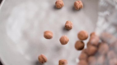 Gevrek çikolata topları ya da gevrek mısır gevrekleri boş bir mutfak seramik kaba kaba kaba ağır çekimde yavaş çekimde yakın çekimde düşüyor.