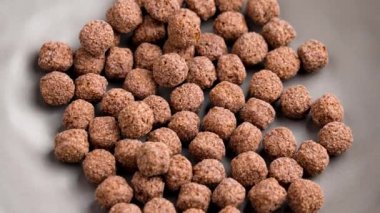 Sağlıklı sabah kahvaltısı hazırlamak için kuru çikolatalı mısır toplarıyla dolu gri mutfak kasesi. Döndürme. Üst görünüm