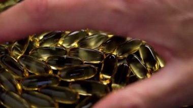 Bir avuç dolusu omega-3 balık yağı kapsülünü ele alalım. Doymamış yağ asitleriyle yarı saydam takviyeler. Yakın plan.