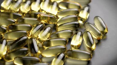 Omega-3 kapsülleri doymamış yağ asitlerinin kaynağıdır. Siyah tabakta yumuşak jel yarı saydam haplar. Beslenme takviyeleri. Döndürme