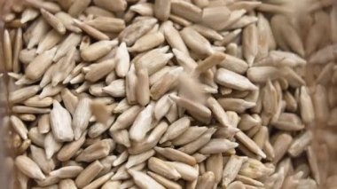 Soyulmuş ayçiçeği çekirdekleri ağır çekimde plastik paketin içine düşüyor. Paketleme marketi alışverişi. Üst Manzara. Ağır çekim. Döndürme. Makro çekim