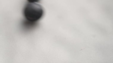 Taze yaban mersinleri yavaş çekimde pürüzsüz nötr tonlu bir yüzey boyunca zarifçe yuvarlanır. Organik olgun çilek. Makro çekim