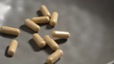 Olası sağlık faydaları olan günlük rutinler için doğal takviyeler. Vitamin kapsülleri gri bir seramik kaseye düşüyor. Yavaş çekim