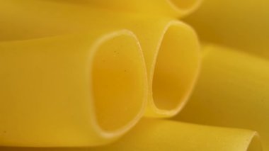 Lezzetli sarı İtalyan cannelloni makarna tüpleri geleneksel pişmemiş buğday malzemesi olarak. Makro. Döndürme