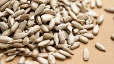 Kahverengi kağıttan bir arka planda organik kabuklu ayçiçeği tohumlarının ham çekirdekleri. Makro atış. Döndürme