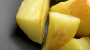 Altın kavrulmuş patates dilimleri, dışı çıtır çıtır ve içi kabarık gri mutfak seramik kasesi. Makro. Döndürme