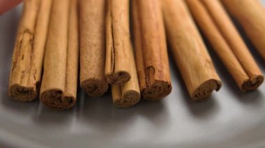 Kurutulmuş aromalı organik tarçın çubukları, Şef tarafından gri bir el sanatları kasesinden alınmıştır.