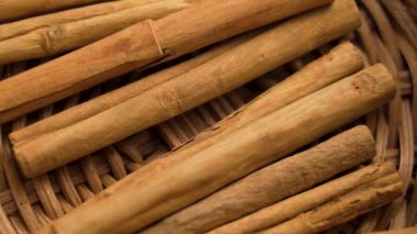 Bir aşçı eli hasır mutfak sepetinden kurutulmuş tarçın çubukları topluyor. Kokulu organik sağlıklı malzeme. Makro çekim