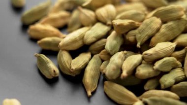 Kurutulmuş kakule kapsülleri. Siyah seramik tabakta organik aromatik kardamon tohumları. Makro. Döndürme