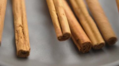 Kuru tarçın çubuklarını lezzetli yemekler için aromatik baharat gibi döküyor. Çiğ organik malzemeler. Yavaş çekim