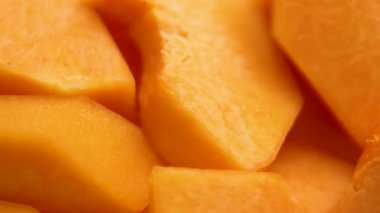 Çiğ organik dilimlenmiş tereyağlı balkabağı. Bol dokulu ve tatlı aromalı. Makro atış. Döndürme