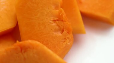 Beyaz bir tabakta dilimlenmiş taze portakallı tereyağı kabağı. Çiğ, tatlı sebze malzemesi. Makro atış. Döndürme