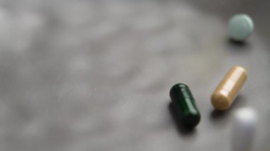 Çeşitli haplar ve ağır çekimde düşen tıbbi kapsüllerin karışımı. Vücut ve zihin sağlığı için doğal maddeler ve kimyasal antibiyotikler