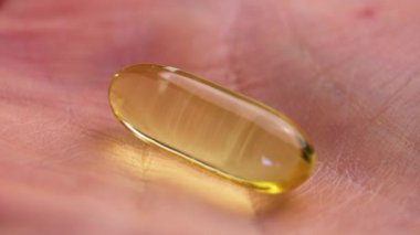 Omega 3 kapsülü kırışıklıkları olan ve doymamış yağ asitleriyle beslenmeye ihtiyacı olan yetişkin bir hastanın elinde.