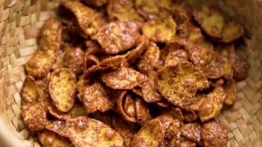 Kuru, sağlıklı kahvaltı malzemesi mısır gevreği, çikolata taneleri kırsal hasır kasede. Makro atış. Döndürme. Üst görünüm