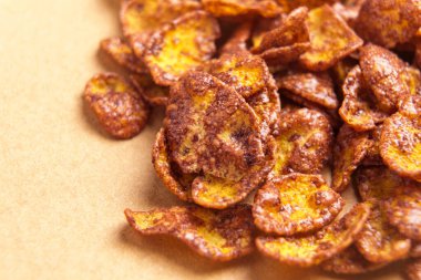 Kahverengi kağıt yüzeyinde pişmemiş mısır gevreği çikolatalı gevrek gevrek. Organik sağlıklı kahvaltı malzemesi. Makro çekim