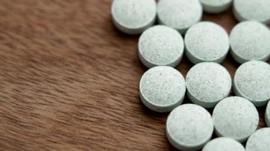 Ahşap arka planda yuvarlak kimyasal ağrı kesici haplar. Sağlık hizmeti konsepti. Döndürme