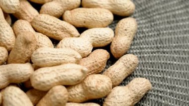 Yeşil sade örülmüş kumaş üzerinde ceviz kabuğu dokuması olan büyük bir grup fıstık. Makro. Döndürme