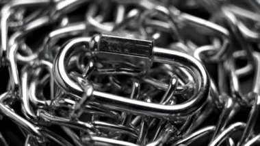 Paslanmaz zincir halkalarının üzerine parlak krom metal tutturucu karabina. Makro. Döndürme