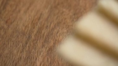 Tahta bir masanın üzerine yavaş çekimde gevrek gevrekler düşüyor, havadar desenli yüzeyi olan organik bir biyo-atıştırmalık için hafif ve sağlıklı bir seçim sunuyor.