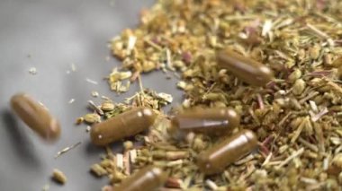 Bitkisel destek kapsülleri yavaş çekimde kurumuş kireç yığınına ya da doğal sağlık için Achillea millefolium bitkisine ve bitki bazlı ilaçlara düşüyor.