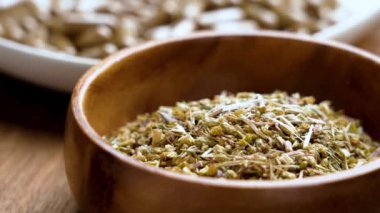 Bitkisel tabletlerin yanında kurumuş şifalı bitkilerle dolu ahşap kase, Ayurveda ve modern bitki özünü doğal destek ve refah bilimi için harmanlıyor. Döndürme