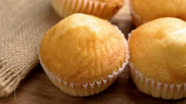 Altın çörekler ahşap bir yüzeyde arka planda desenli bir çuval bezi ile dinleniyor, kırsal cazibe ve ev yapımı kalite sergiliyorlar. Döndürme