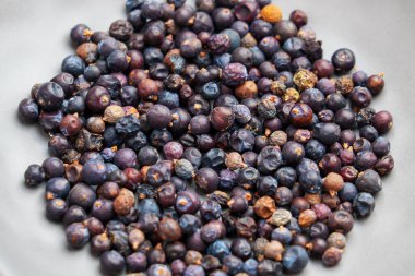 Dried Juniper berries in gray plate as a organic natural superfood used in traditional and contemporary health-focused diets. Top view clipart