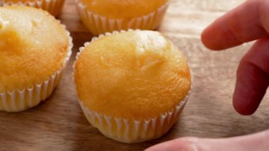 Gurme bir el, ahşap bir tahtanın üzerinde altın bir kek topluyor. Yumuşak ve yumuşak dokular organik malzemelerle yapılır, tatlı hoşgörü için mükemmeldir.