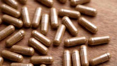 Ahşap bir yüzeyde, bitkisel malzemelerle dolu doğal kapsüller. Doğal sağlık ve bütünsel sağlık kavramı. Yakın plan. Döndürme