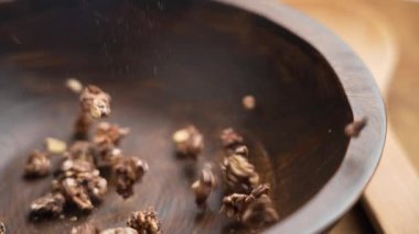 Koyu bir ahşap kaseye düşen gevrek çikolata tanecikleri, besleyici bir aperatifin hareketlerini ve dokusunu yakalıyor. Sağlıklı yaşam tarzı kavramı