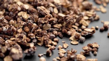 Siyah bir yüzeyde siyah çikolata parçacıkları olan gevrek organik tanecikler. Yüksek miktarda protein ve lif, dengeli bir diyet için mükemmel. Sağlıklı gıda ve sağlık konsepti. Döndürme. Makro çekim