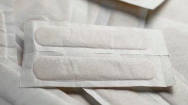 Steril eczane ambalajında tıbbi yapışkan bandaj görüntüsü. İlk yardım ve yara bakım aletleri, hijyenik kullanım için tasarlanmış. Döndürme