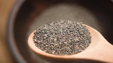 Tahta kaşıktan Chia tohumları dökülüyor. Besin zengini süper yiyecekler yüksek omega-3 yağ asitleri, lif ve antioksidan içeriyor. Sağlıklı beslenme ve beslenme için mükemmel.