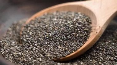 Tahta bir kaşığa organik chia tohumları dökülüyor. Bu süper yiyecekler omega-3 yağ asitleri, lif ya da antioksidan açısından zengindir, sindirimi destekler. Meyve suyu, yoğurt ve fırın için mükemmel.