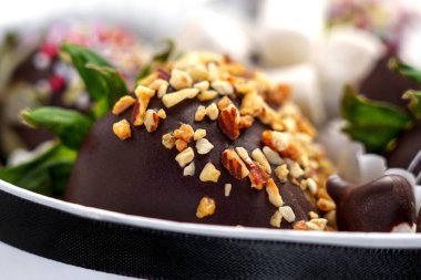 Chocolate-dipped strawberry topped with chopped nuts, highlighting the unique intricate textures and rich details of this decadent dessert. Macro shot clipart