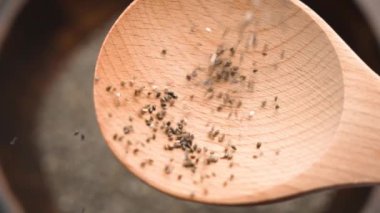 Chia tohumlarından oluşan bir şelale pürüzsüz bir tahta kaşığa dökülüyor. Yakından bakınca, küçük taneler ve doğal dokular ön plana çıkıyor. Yavaş çekim