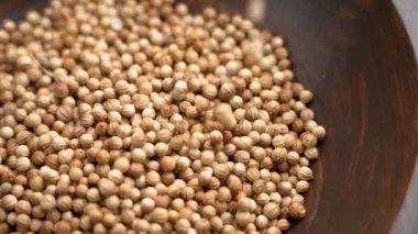 Kurutulmuş kişniş ya da kişniş çekirdeği (Coriandrum sativum) kırsal bir ahşap kaseye düşer. Organik aromatik baharat. Ağır çekim. Döndürme