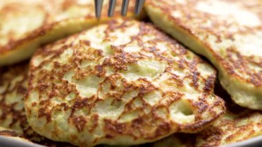 Rendelenmiş kabak, badem sütü, yumurta ve psyllium ile taze pişmiş börek. Gümüş bir çatal altın gevrek yüzeyi deliyor. Kapat.