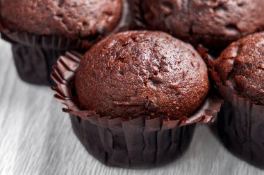 Yağlı desenli taze çikolatalı çörekler ve eskimiş arka planda açık renkli kağıt bardaklarda derin çatlaklar. Kapat. 