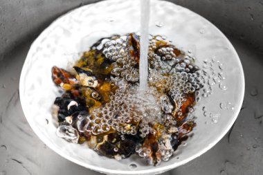 Mutfak lavabosunda akan suyun altında durulanan taze midye manzarası.