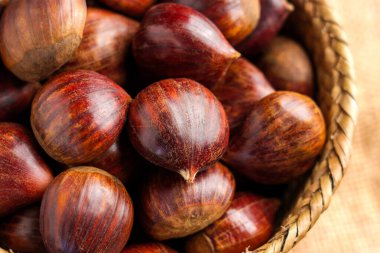 Dokuma sepetinde desenli kabukları olan parlak kahverengi kestanelerin yakın çekim görüntüsü. Organik bir çiftlikten yeni toplanmış.