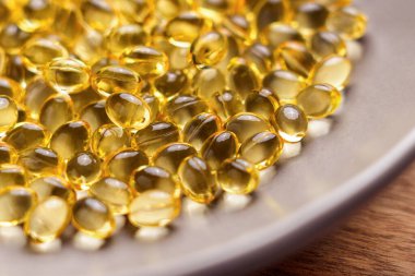 Altın şeffaf D-3 vitamini gümüş bir tabakta istiflenmiş. Kapat.