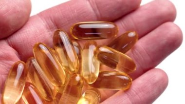 EPA ve DHA 'lı Omega-3 kapsülleri. Altın yarı şeffaf yumuşak jeller beyaz arkaplanı kapatır
