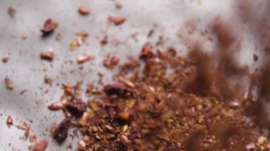 Organik kakao tozu, keten tohumu ve kurumuş siyah böğürtlenlerden oluşan kabartma karışımı yavaş çekimde boş bir mutfak kasesine düşüyor. Üst Manzara. Makro