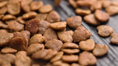 Siyah kağıda dökülen kalp şeklinde çıtır kedi maması. Ağır çekim. Kediler için vitamin ve besin kaynağı